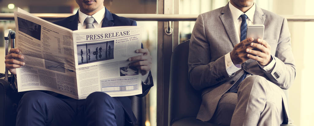 Two Men In Business Suits Reading Newspaper and Checking Device